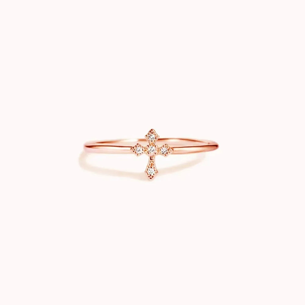 Delicate diamond cross ring in rose gold with a thin band.