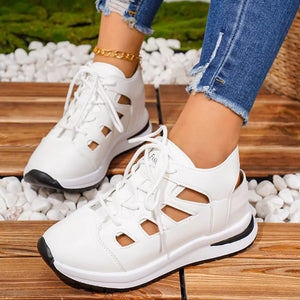 Chic white round toe lace-up sneakers with cut-out details and a black sole.