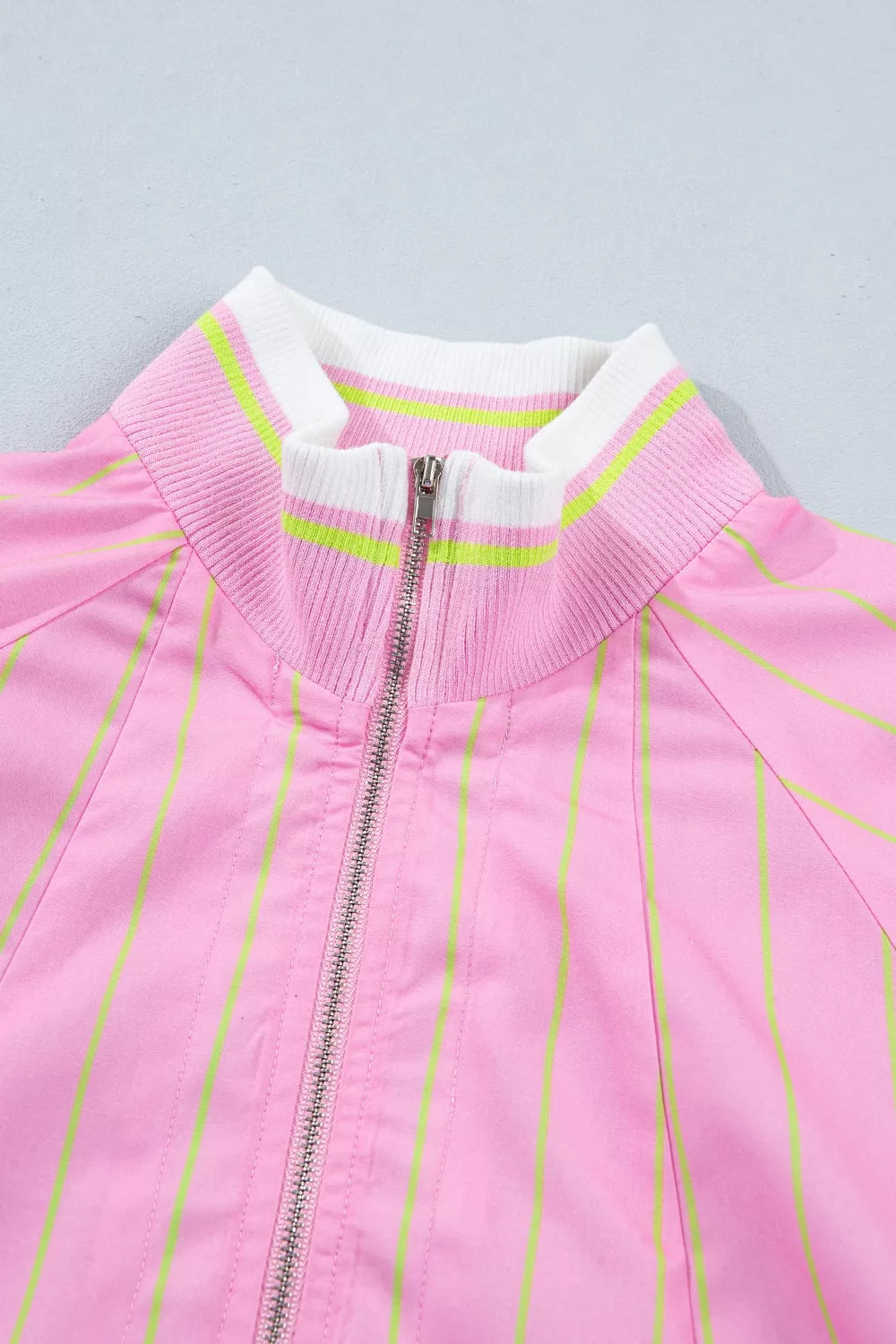 Pink striped half-zip polo shirt with white and lime green ribbed collar and cuffs.