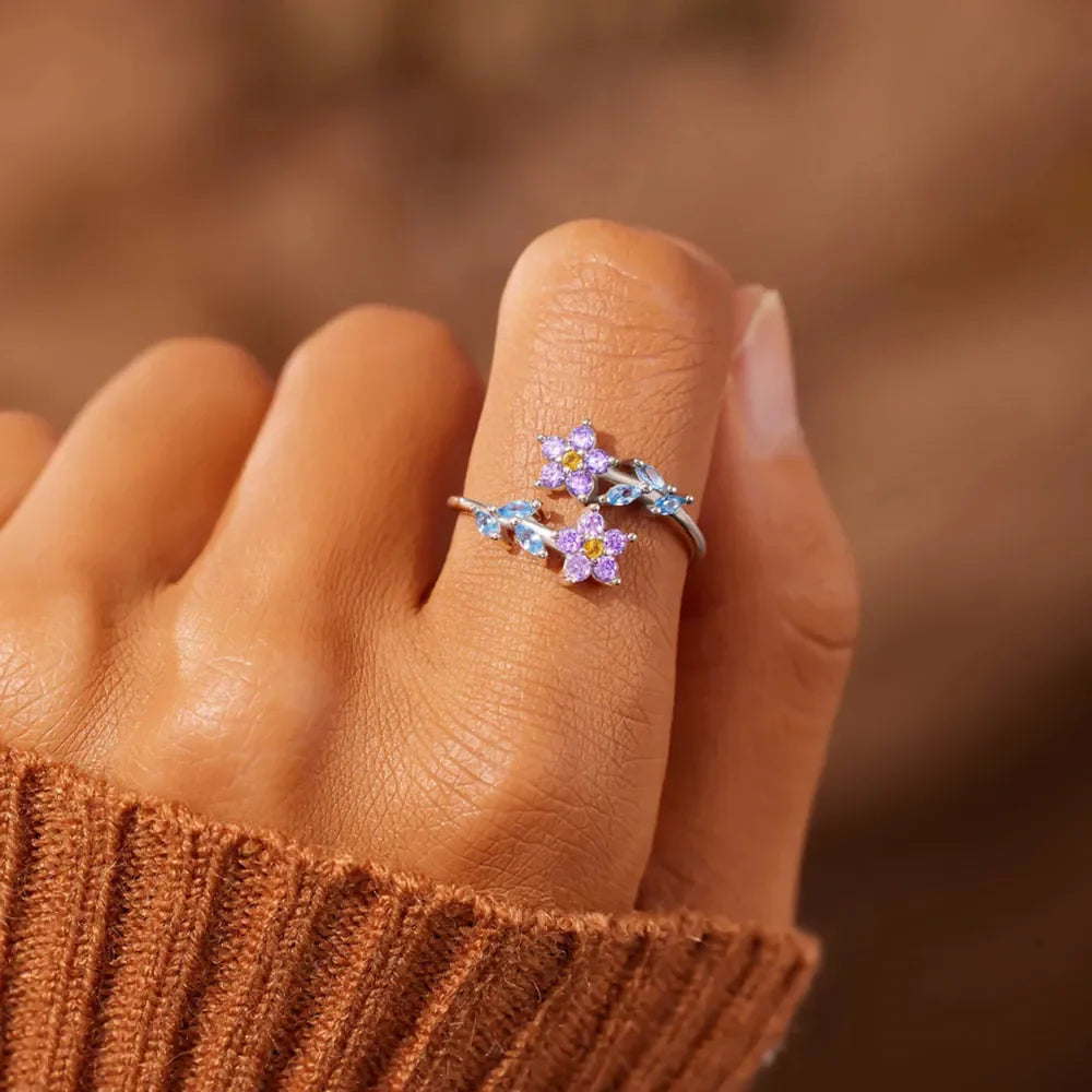 Silver bypass ring with purple and blue floral zirconia details.