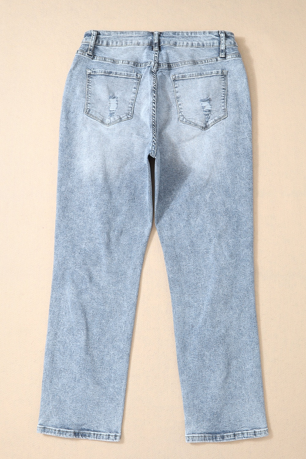 Distressed wash light blue denim slim leg jeans with ripped back pockets.