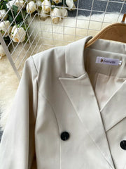 Cream double-breasted blazer with black buttons and notched lapels.
