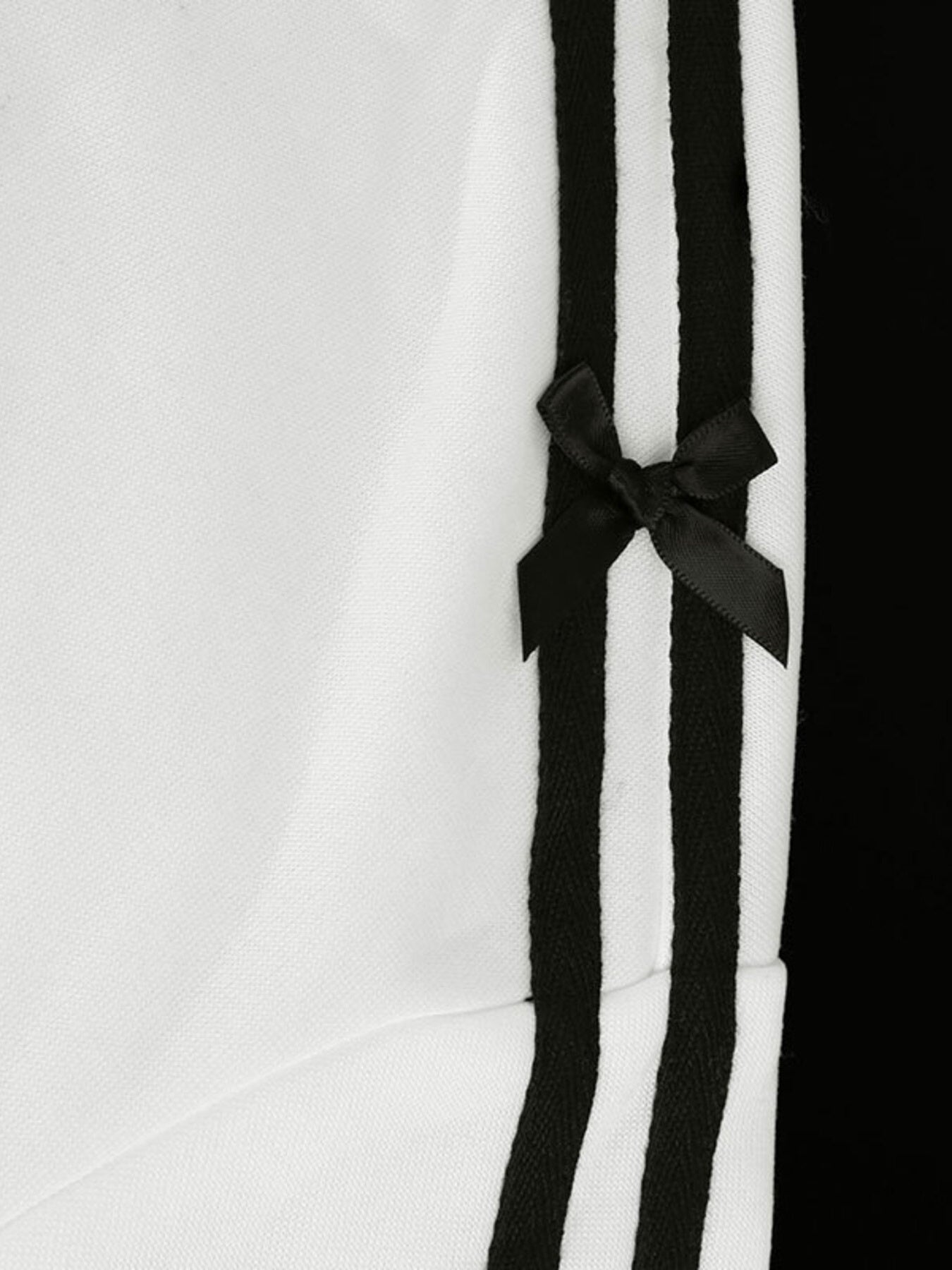 White zip-up hoodie with black stripes and a black bow detail.
