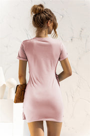 Blush pink jersey mini dress with short sleeves and knot-front detail.
