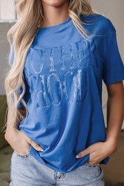 Blue oversized graphic tee with "MOTHERHOOD" text, crew neck, short sleeves.
