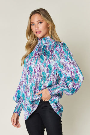 High neck abstract print blouse in sky blue and red-violet with smocked cuffs.