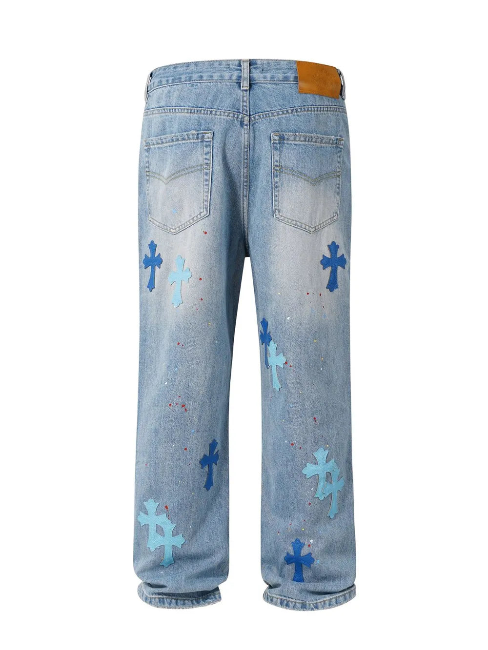 Medium wash denim jeans with blue embroidered cross patches and paint splatters.