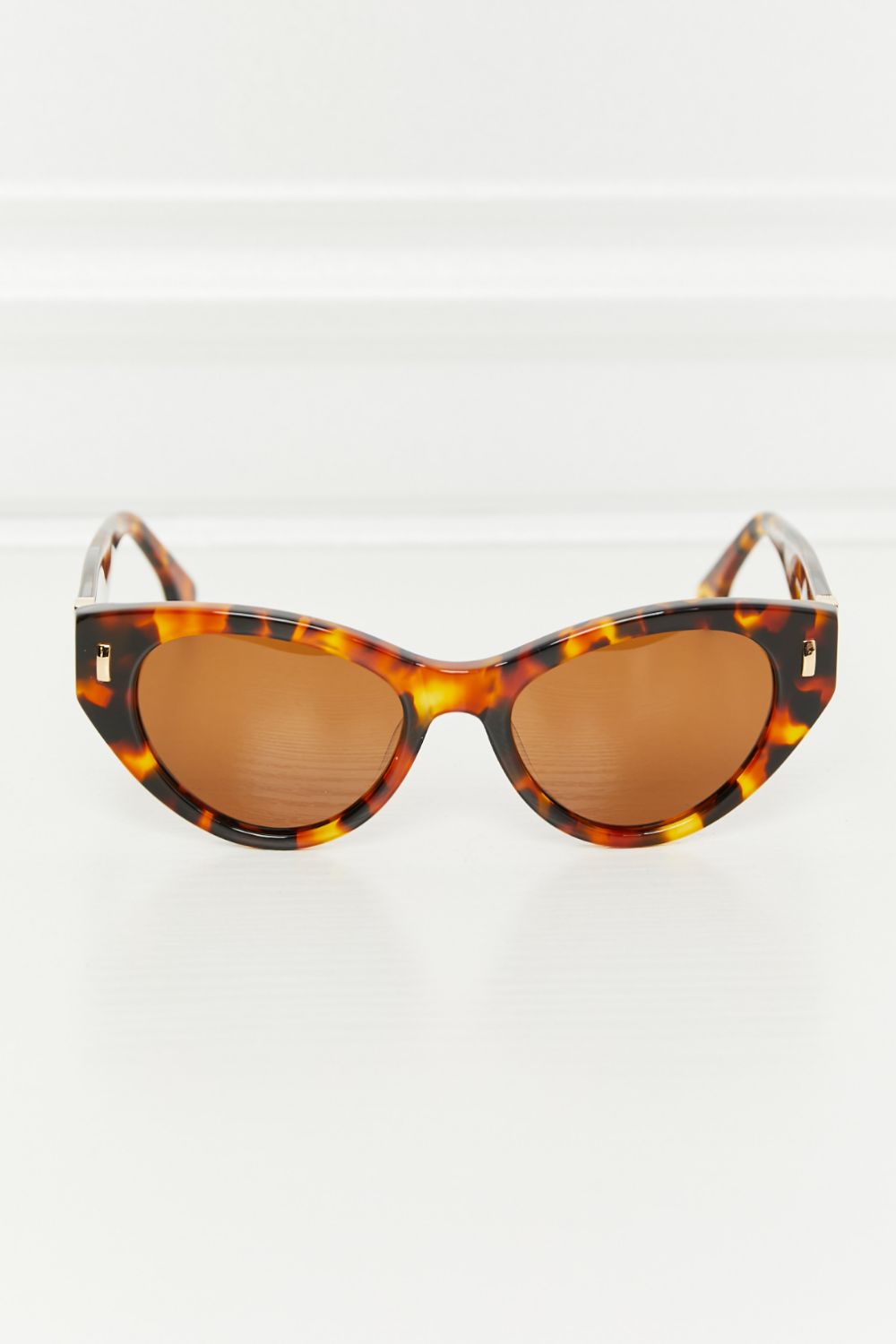 Cat-eye tortoise shell acetate sunglasses with brown lenses and gold accents.