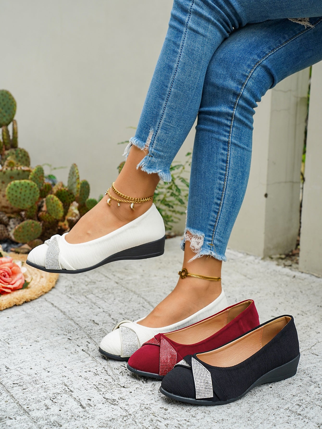Rhinestone adorned slip-on wedge flats in red, beige, and black with textured fabric and a subtle wedge heel.