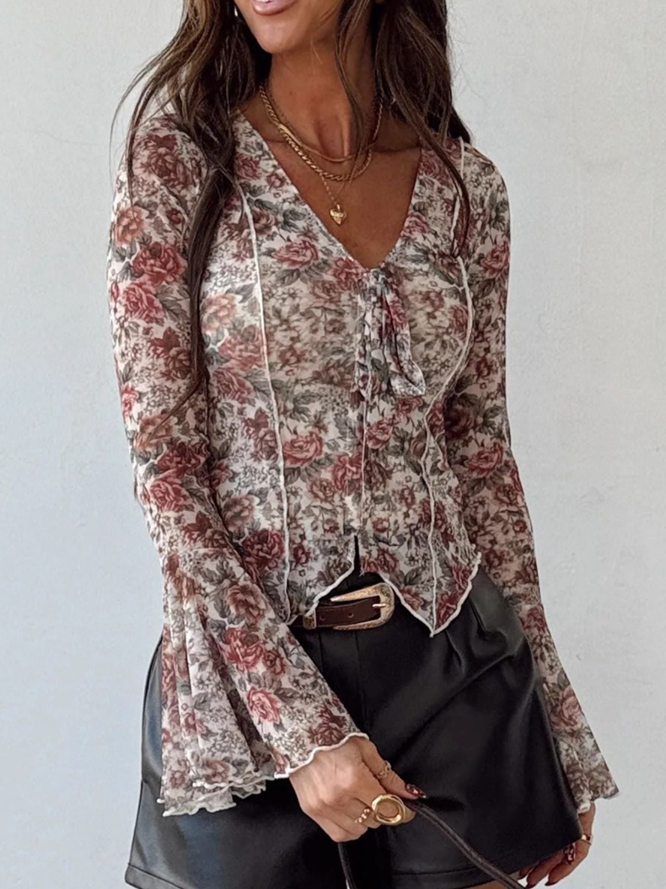 Charming floral print sheer blouse with tie neck and ruffled bell sleeves.