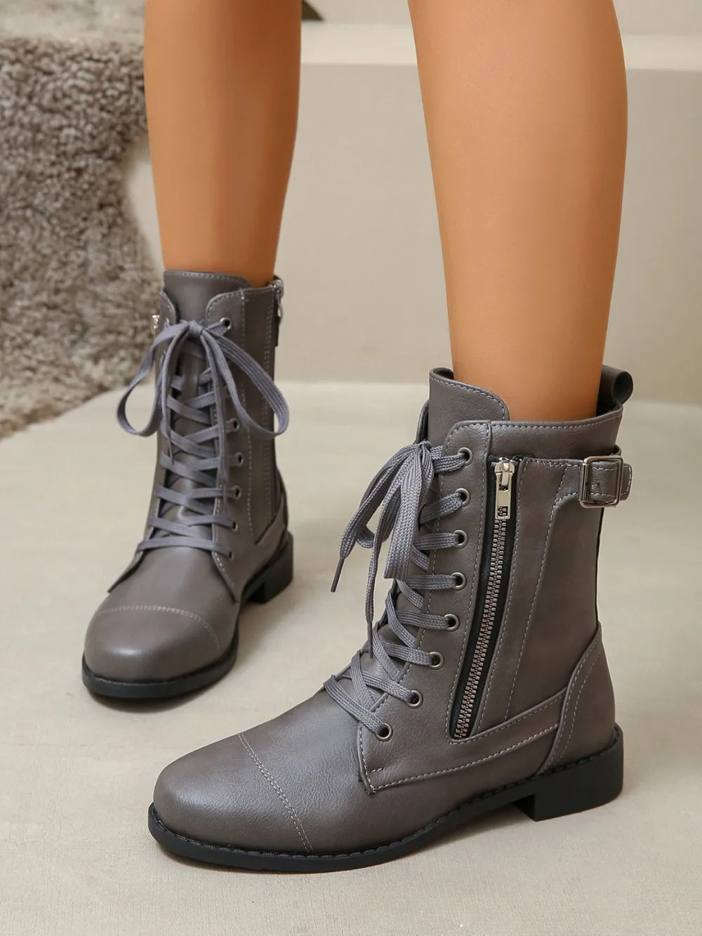 Dark gray combat boots with lace-up front, side zipper detail, and buckle strap.