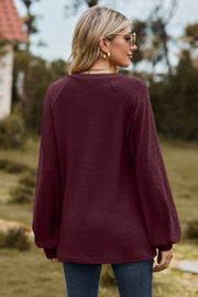 Burgundy waffle knit raglan sweater with laser cut diamond pattern sleeves.