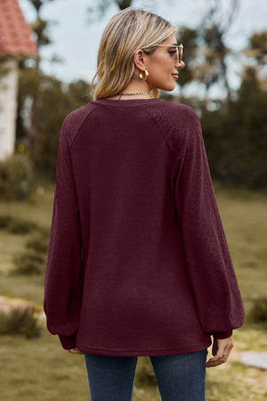 Burgundy waffle knit raglan sweater with laser cut diamond pattern sleeves.