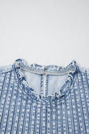Denim blouse with ruffled neckline and vertical pleats.