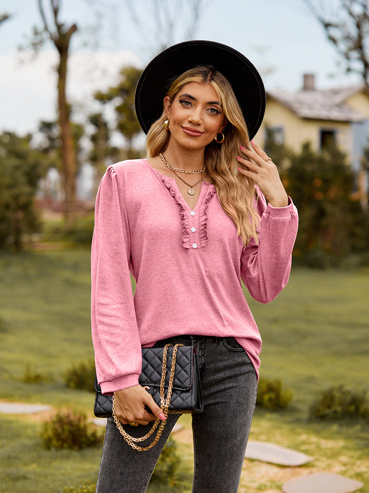 Pink ruffled henley blouse with button detail and long sleeves.