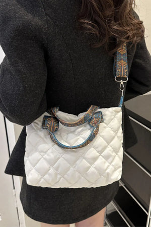 White quilted satchel bag with patterned strap and handles.