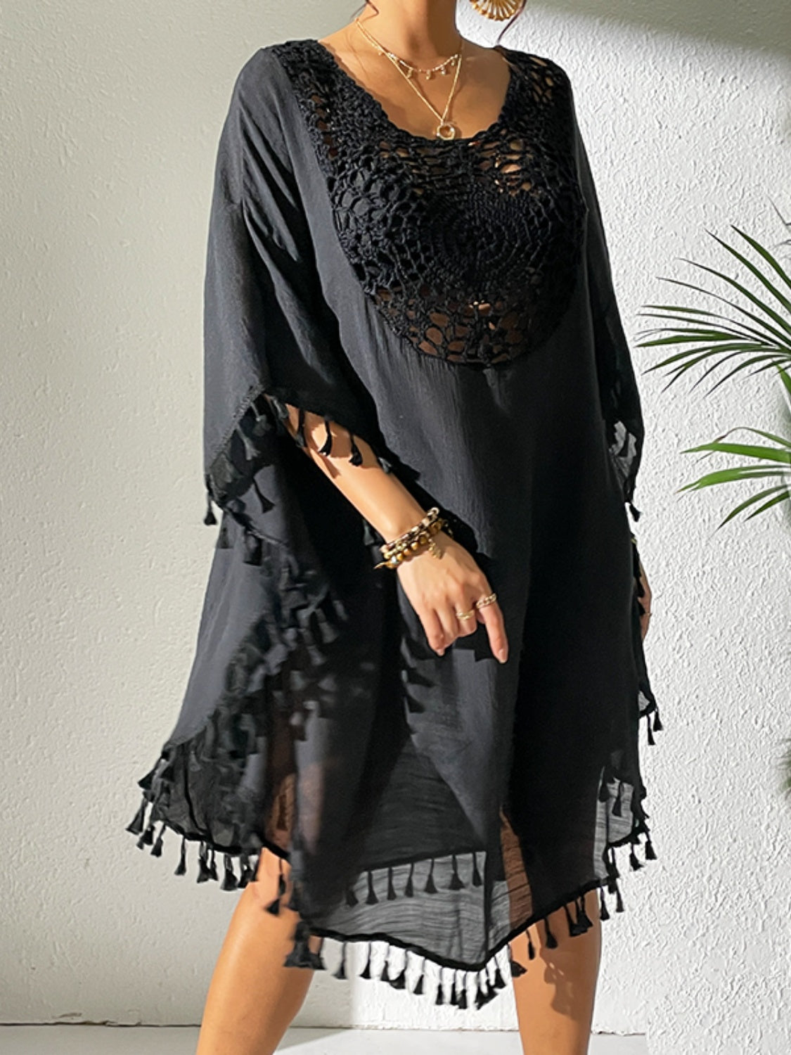 Black crochet yoke kaftan dress with tassel trim and wide sleeves.