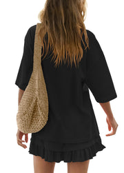 Black ruffled tee and skirt set with a woven crossbody bag.