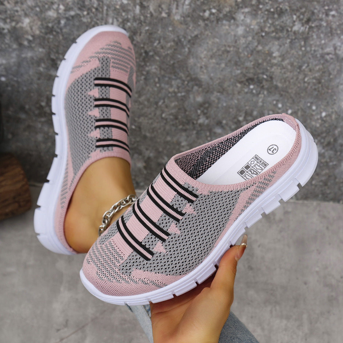 Pink and gray knit slip-on sneakers with black stripe detail and white soles.