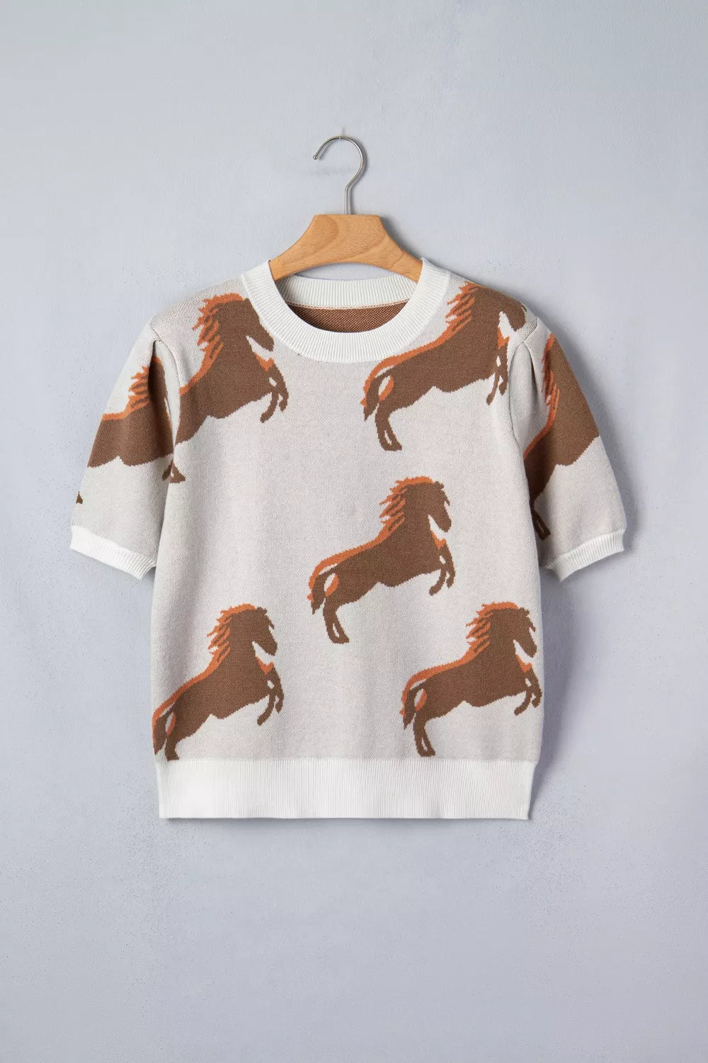 Beige knit sweater with all-over brown horse print and puff sleeves.