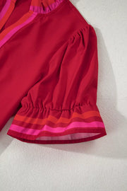 Ruffled maternity blouse in red with striped neckline and sleeve cuffs.