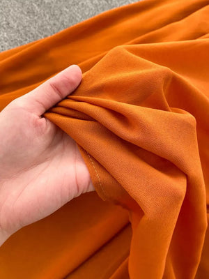 Orange red maternity dress fabric detail, showing flowy material and texture.