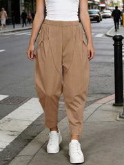 Camel harem joggers with pockets and a pinstripe detail, styled with white sneakers.