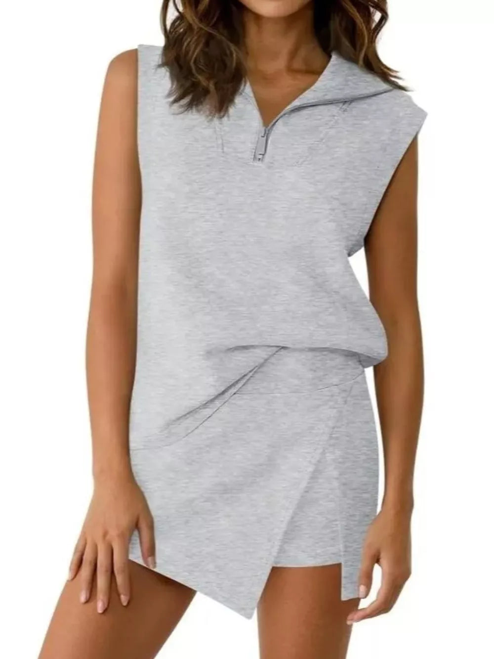 Light gray sleeveless quarter-zip top and asymmetrical skort ensemble