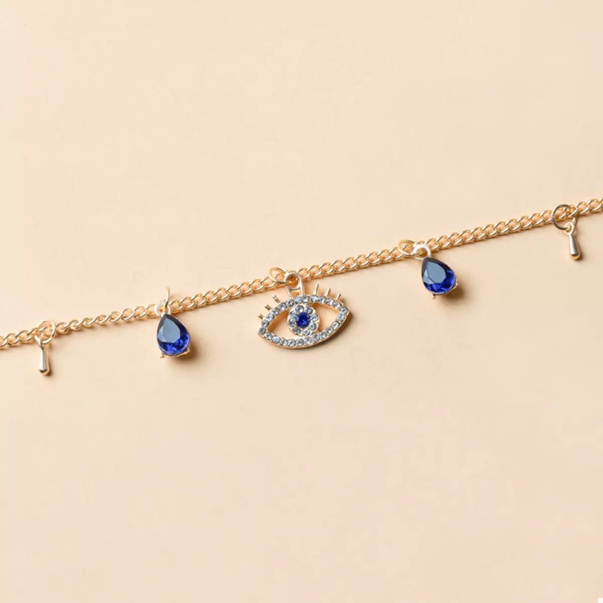 Gold evil eye charm necklace with blue teardrop accents and crystal details