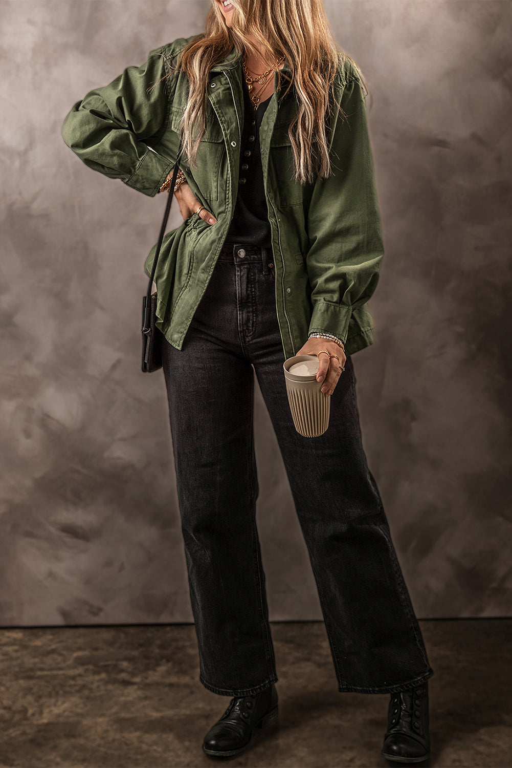 Army green military-inspired jacket with drawstring waist and button front, styled with black jeans.