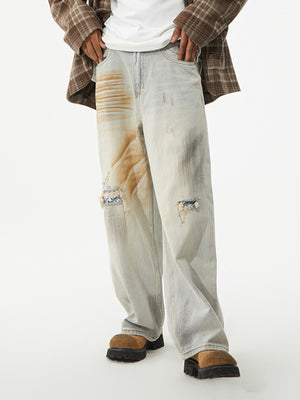 Light wash distressed wide-leg jeans with unique graphic patches and ripped details.