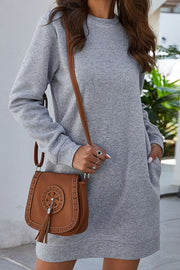 Light gray sweatshirt dress with slant pockets and long sleeves.