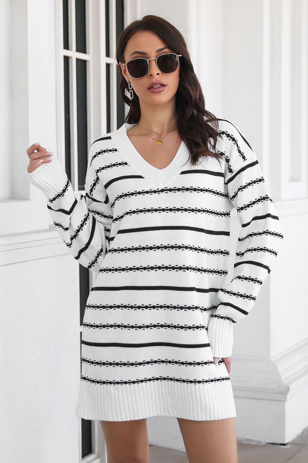 White and black striped knit mini dress with V-neck and long sleeves.