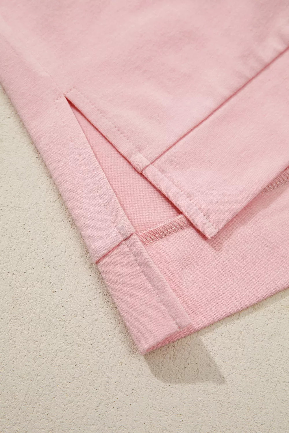Pink cotton t-shirt with side slits and dimensional applique flower detail.