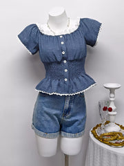 Blue ruffled smocked maternity blouse with puff sleeves, white lace trim, and decorative buttons.