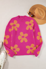 Oversized knit sweater in cerise with large orange floral print, crew neck, and long sleeves.