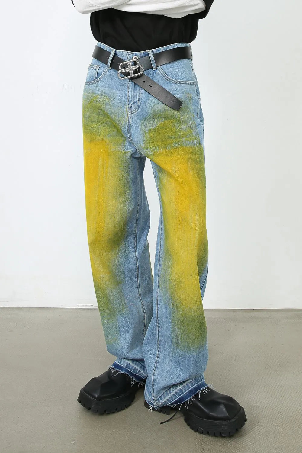 Oversized denim jeans in medium wash with bold yellow and green spray paint effect.