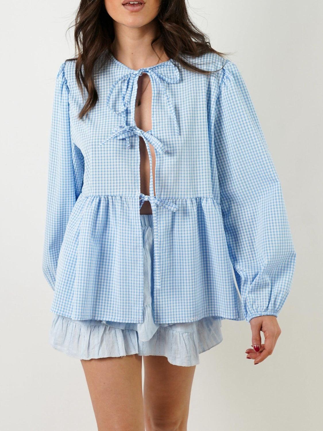 Light blue gingham tie-front peplum blouse with voluminous sleeves and ruffled hem shorts.