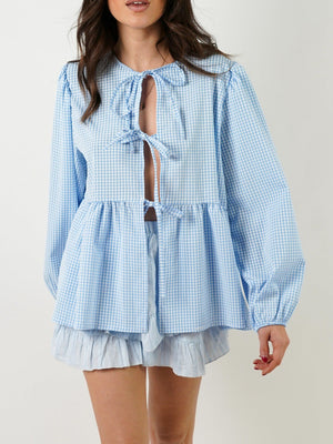 Light blue gingham tie-front peplum blouse with voluminous sleeves and ruffled hem shorts.