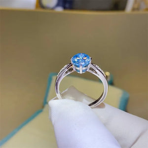 Sterling silver ring with a bright blue moissanite gemstone and diamond halo.