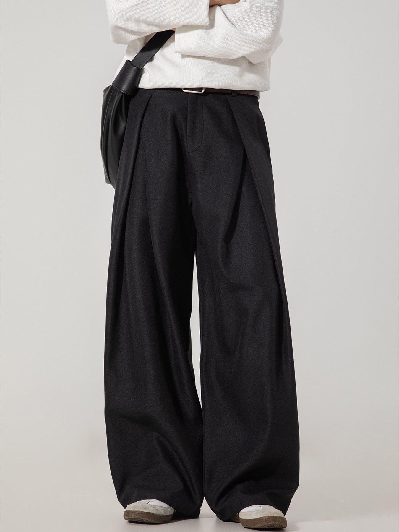 Men's black wide-leg trousers with pleats and a belted waist.