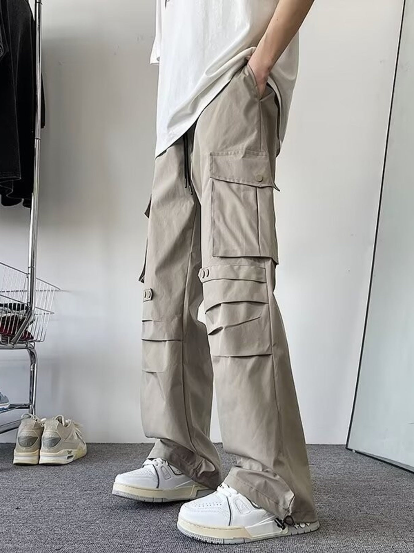 Khaki wide-leg cargo pants with multiple flap pockets and adjustable ankle straps.
