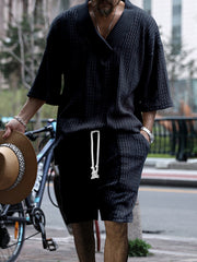 Black cable-knit V-neck two-piece set with short sleeves and drawstring shorts.
