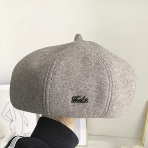 Woolen beret in beige with paneled design and metal accent.