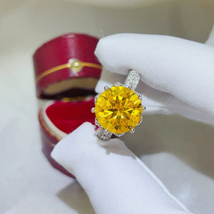 Yellow moissanite solitaire ring with diamond-accented band in a jewelry box.