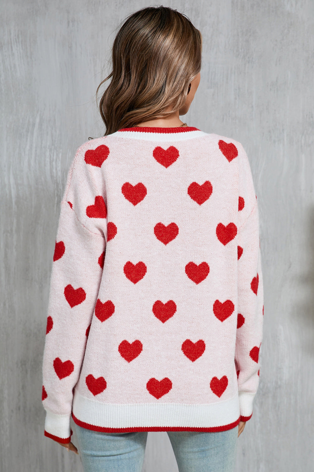 Pink acrylic crewneck sweater with red heart intarsia pattern and contrast trim.