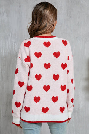 Pink acrylic crewneck sweater with red heart intarsia pattern and contrast trim.