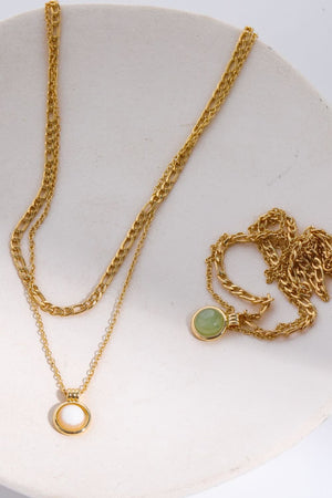 Gold layered necklaces with green aventurine and white orb pendants.