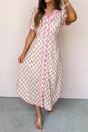 Floral V-neck midi dress with button front, scalloped trim, and short sleeves in blush pink.