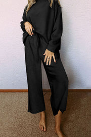 Black loungewear set with textured pattern, drop sleeves, and wide-leg pants with drawstring waist.